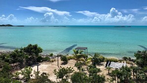 A beach with clear turquoise water, a checkered area, and palm trees.