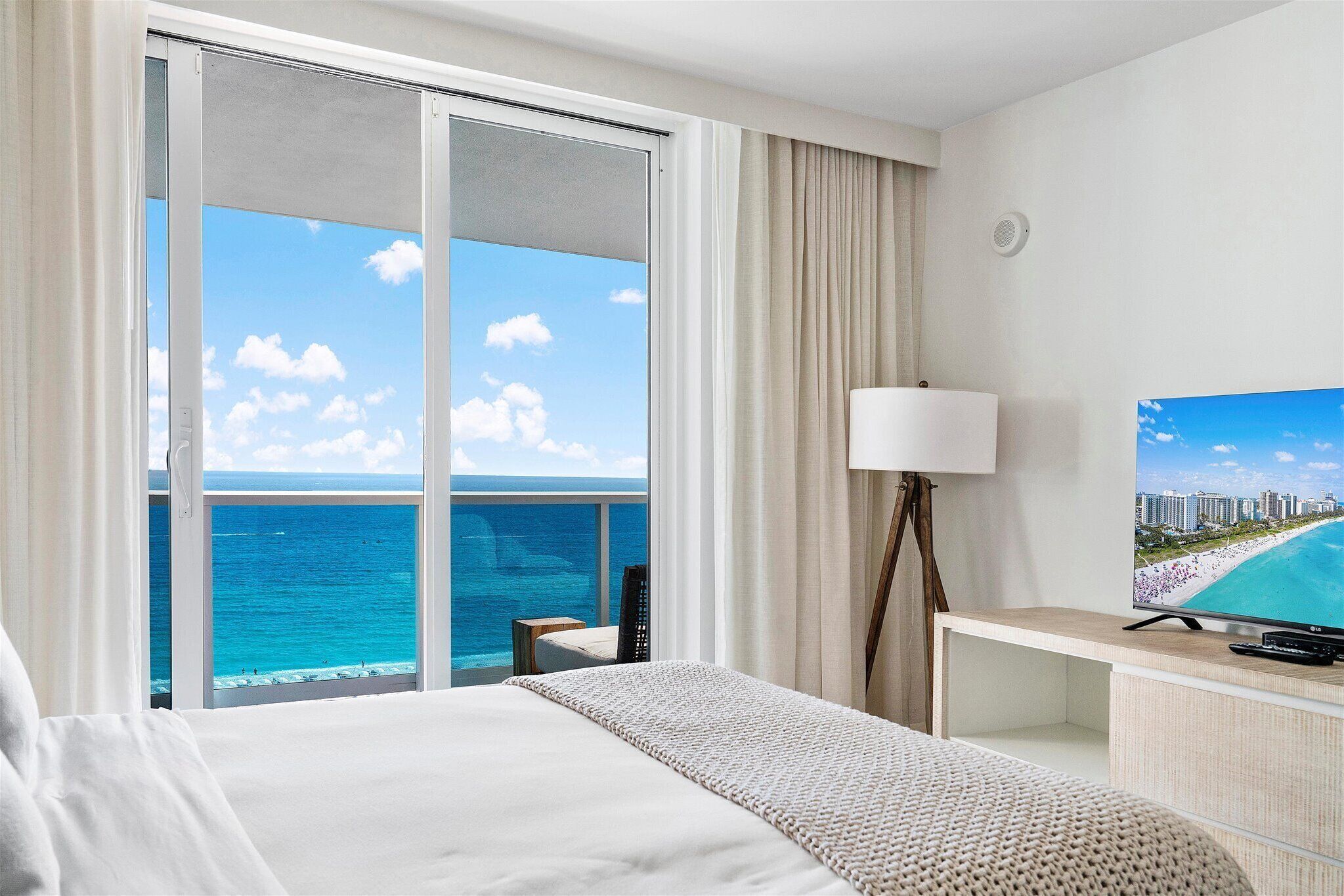 Ein Hotelzimmer mit Bett, Fernseher, Lampe und Meerblick.
