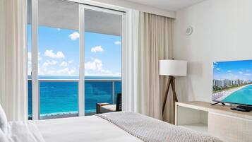 Ein Hotelzimmer mit Bett, Fernseher, Lampe und Meerblick.