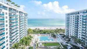 Un hotel moderno de altura con varios balcones que dan a una playa y un área de piscina.