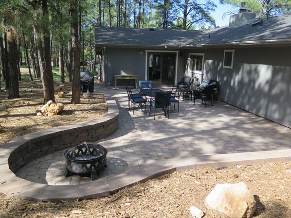 A patio area with a stone fire pit, outdoor furniture, and a stone retaining wall.