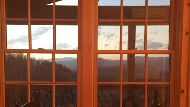 Una mesa de comedor con dos copas de vino, una botella y un plato verde.