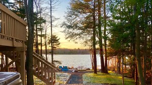 A wooden deck with a staircase leading to a viewing area overlooking a lake, surrounded by trees. - Lakefront w Sauna/Hot Tub/Boats/Beach/Firepit/Pool table,close to Kalahari & Ski (Pocono Summit)