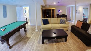 A living room with a pool table, a sofa, and a coffee table. - Lakefront w Sauna/Hot Tub/Boats/Beach/Firepit/Pool table,close to Kalahari & Ski (Pocono Summit)