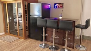 A bar area with a refrigerator, a neon sign, and three bar stools. - Lakefront w Sauna/Hot Tub/Boats/Beach/Firepit/Pool table,close to Kalahari & Ski (Pocono Summit)