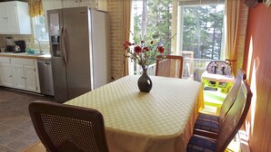 A dining area with a table, chairs, a vase with flowers, and a view of the outdoors. - Lakefront w Sauna/Hot Tub/Boats/Beach/Firepit/Pool table,close to Kalahari & Ski (Pocono Summit)