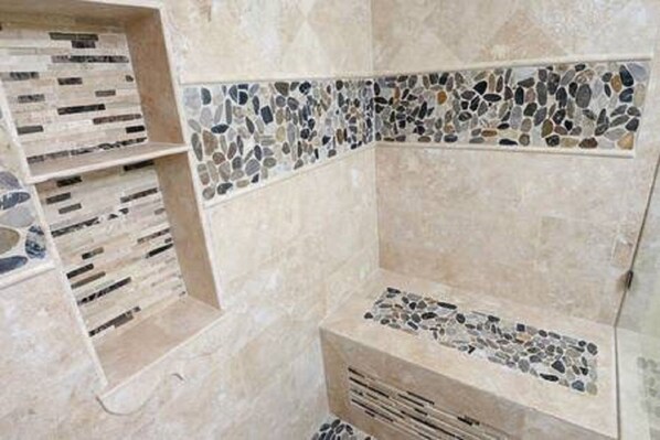 Une salle de bain avec des bordures en mosaïque de pierre et un banc intégré.