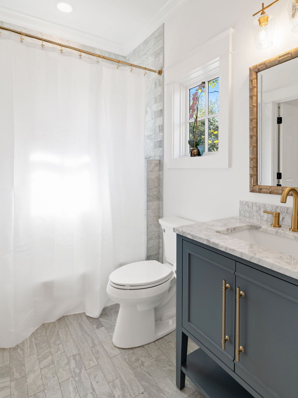 A bathroom with a white toilet, a marble sink, and a shower curtain.