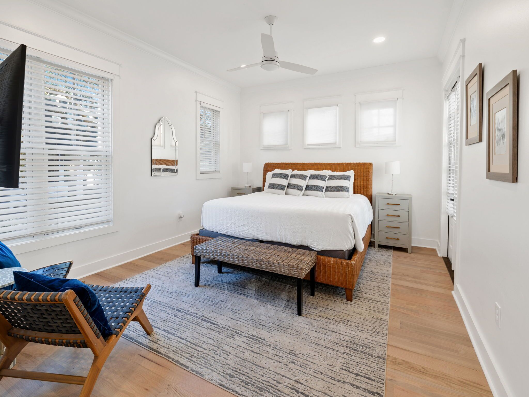 A bedroom with a bed, a ceiling fan, a nightstand, a chair, and a window with blinds.