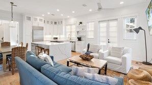 A modern living room with a blue sofa, white armchairs, and a coffee table.