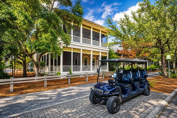 A two-story building with a covered porch and a golf cart parked in front. - Elegant Camp District Home with Electric Cart, 6 Bikes & Watercolor Beach Club Access (Santa Rosa Beach)