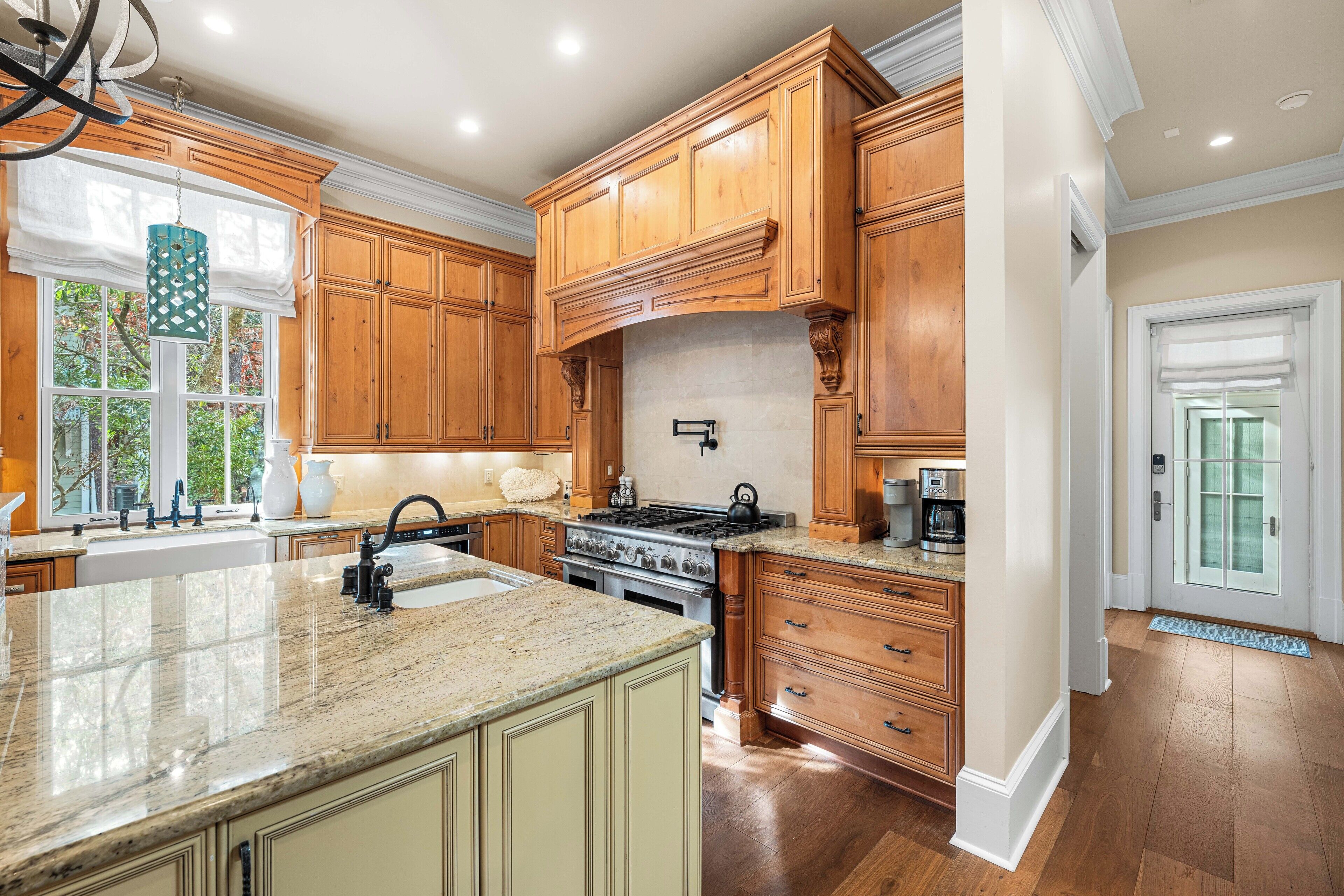 A kitchen with wooden cabinets, a granite countertop, a stove, and a sink.
