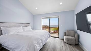 A bedroom with a bed, a chair, and a balcony with a view.