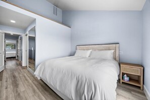 Un dormitorio con una cama grande, cabecera de madera y una mesita de noche con una cesta de mimbre.