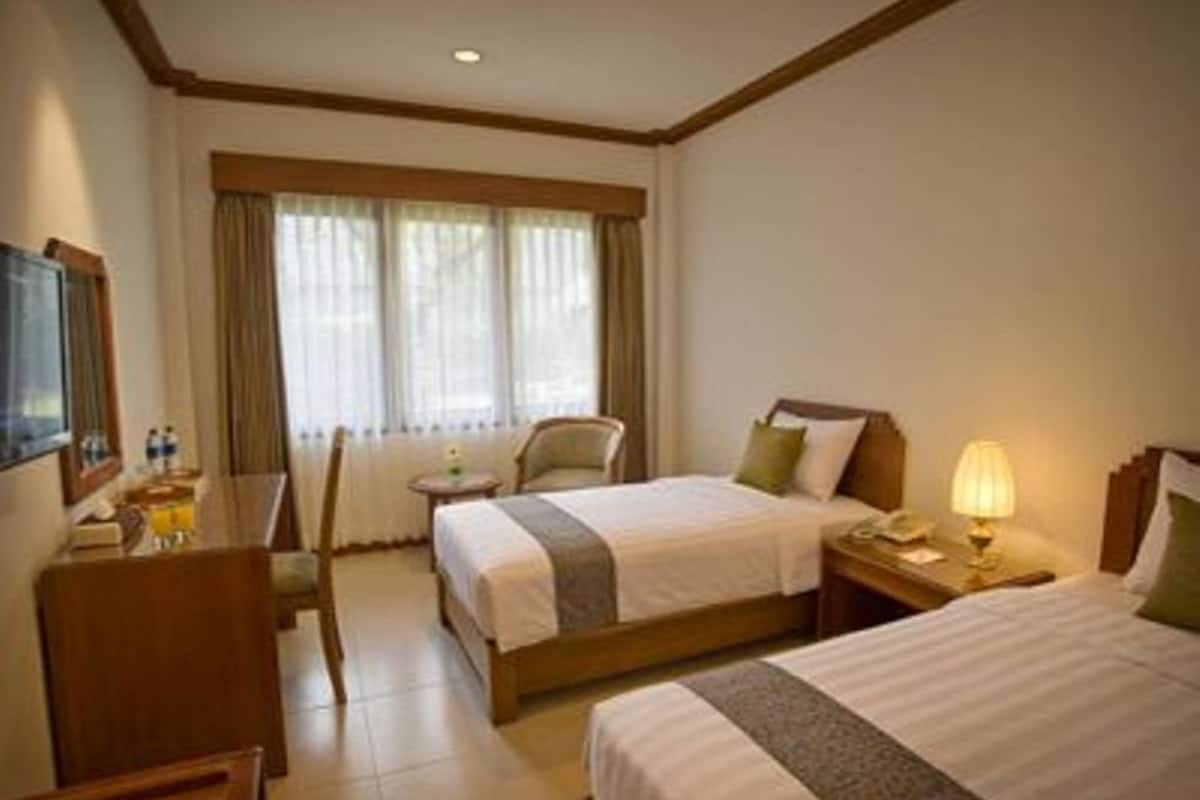 A hotel room with two beds, a desk, a chair, and a TV.