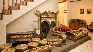 Interior tradicional com escadaria, parede decorativa e área de estar com almofadas e uma mesa.