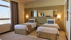 A hotel room with two beds, a large mirror, and a city view. - Gulf Executive Residence (Manama)