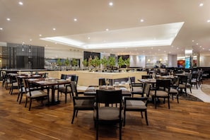 Un restaurante moderno con suelo de madera, sillas oscuras y una zona de bar central.