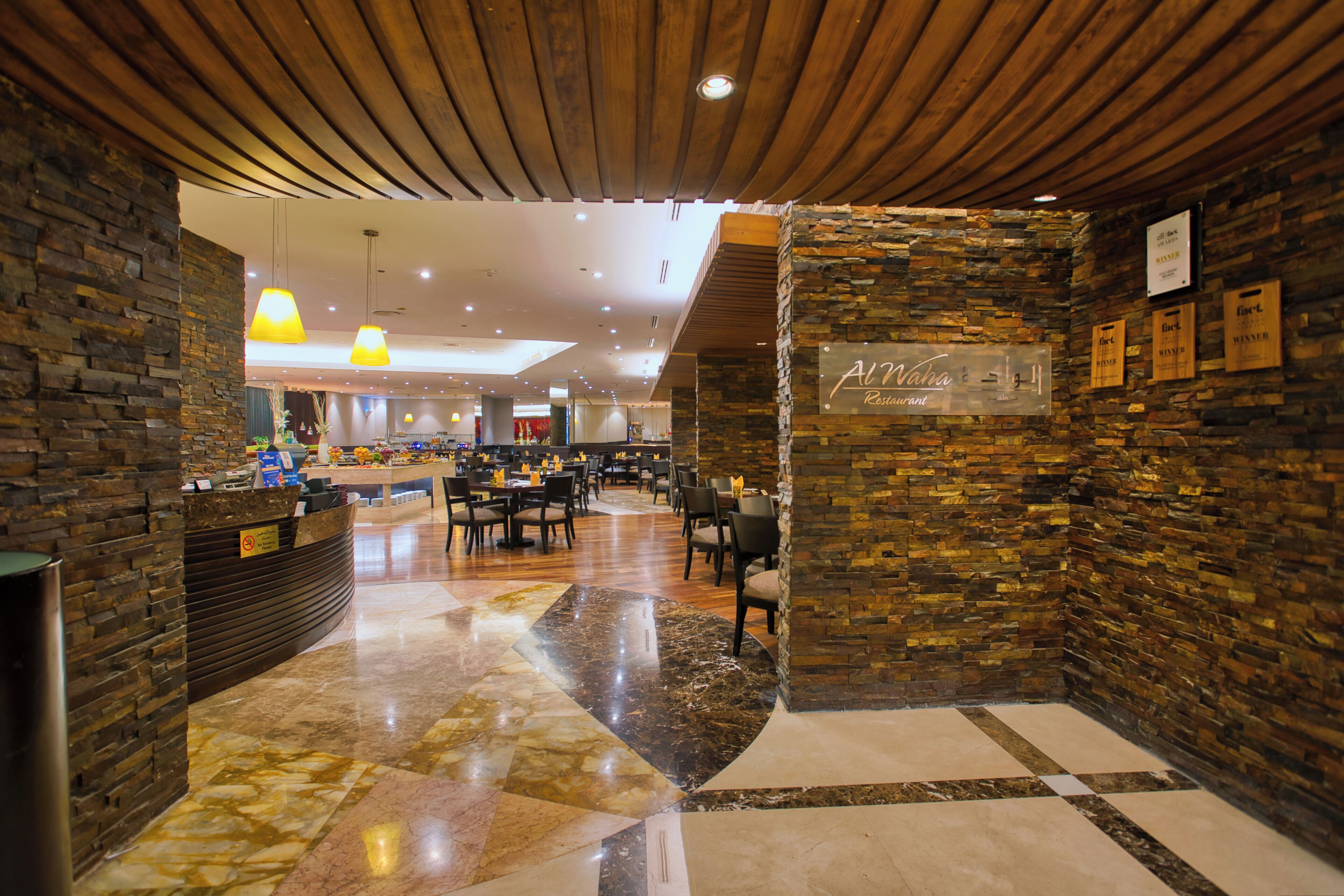 A restaurant interior with a stone wall, wooden ceiling, and a checkered floor pattern.