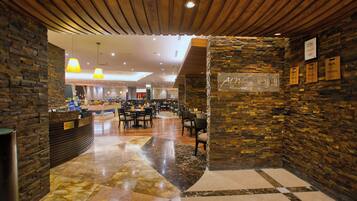 A restaurant interior with a stone wall, wooden ceiling, and a checkered floor pattern.