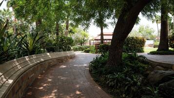 A curved brick pathway in a landscaped area with trees and shrubs.