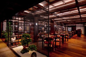A spacious indoor area with wooden flooring, multiple seating arrangements, and a central decorative plant. - Gulf Executive Residence (Manama)