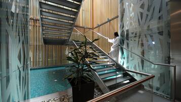 A modern interior with a glass staircase, a wooden slatted wall, and a potted plant.