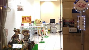 A hotel entrance with a neon sign, a reception desk, and a teddy bear decoration.