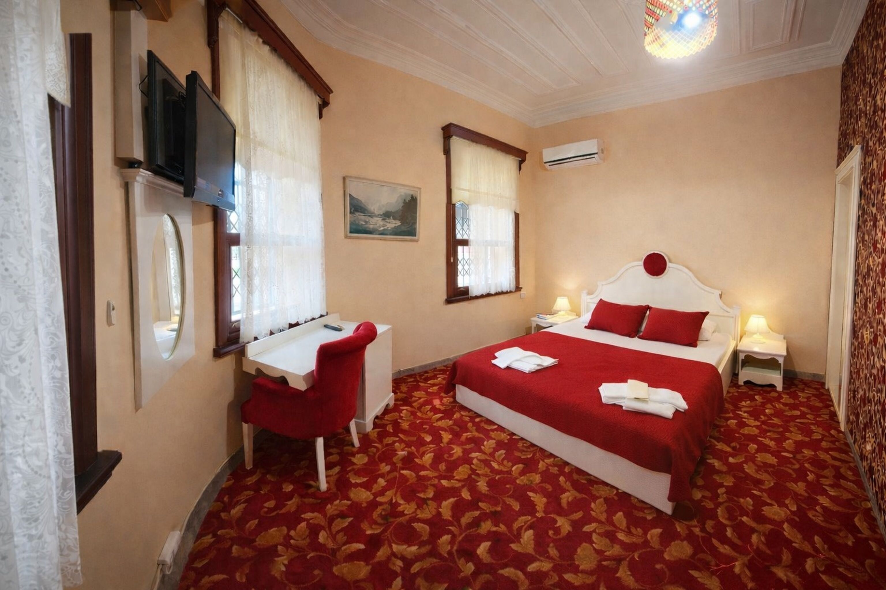 Habitación de hotel con cama, escritorio, silla y televisor.