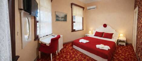 Habitación de hotel con cama, escritorio, silla y televisor.