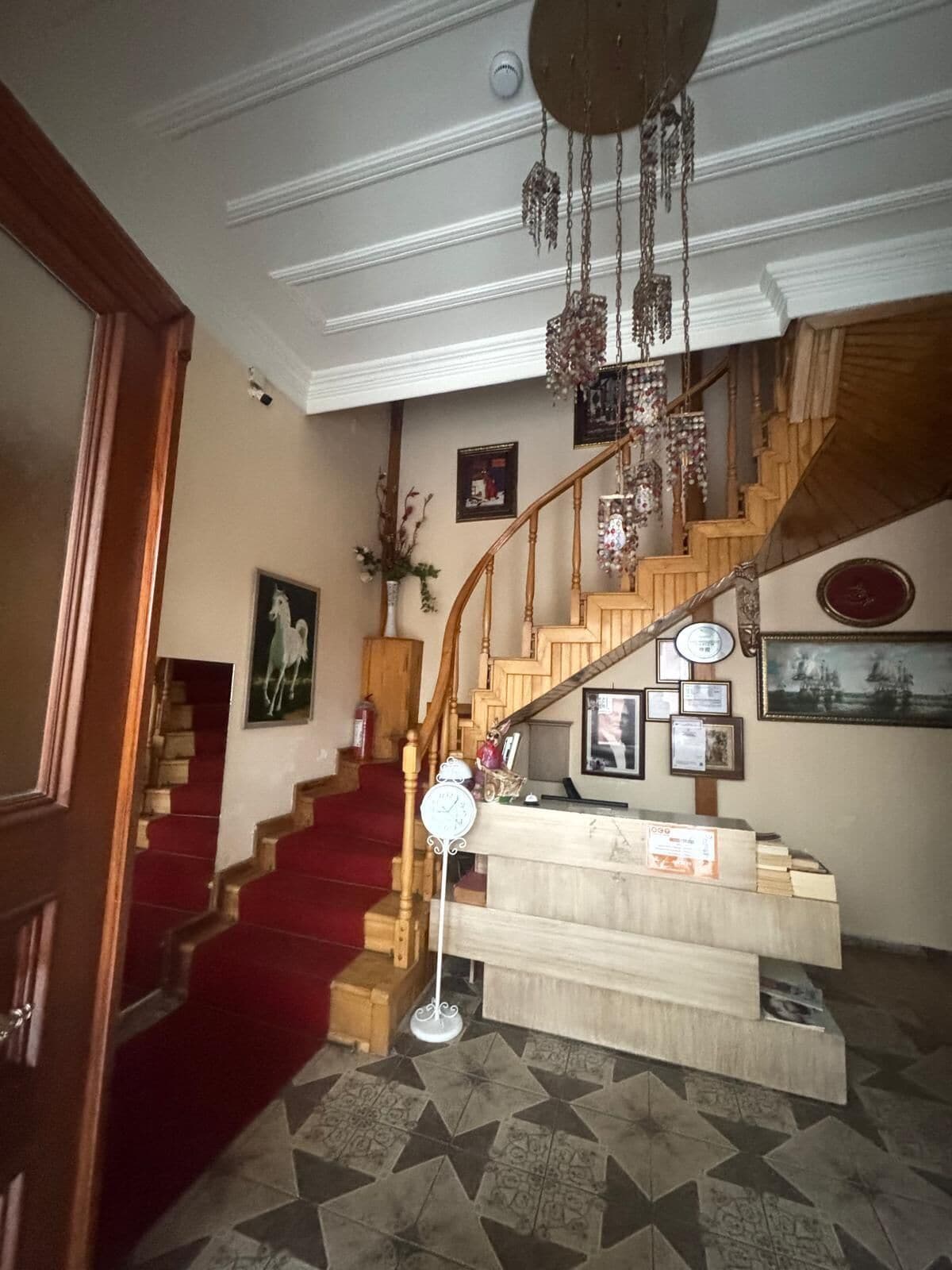 Eine prächtige Treppe mit Holzvertäfelung, ein Teppich im Landehausstil und ein Kronleuchter.