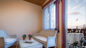 Un balcón con mobiliario de mimbre, una mesa con bandeja y vista al cielo.