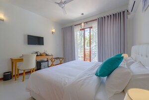 Hotelkamer met een bed, bureau, stoel, televisie en raam met gordijnen.