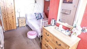 A bedroom with a bed, dresser, vanity, and a large mirror.