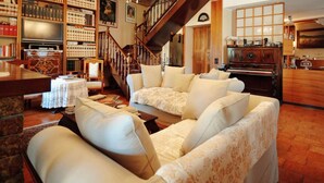 Uma sala de estar acolhedora com um sofá, um piano e uma estante repleta de livros.