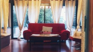 Uma sala de estar aconchegante com um sofá vermelho, uma mesa de centro de madeira e um lustre.