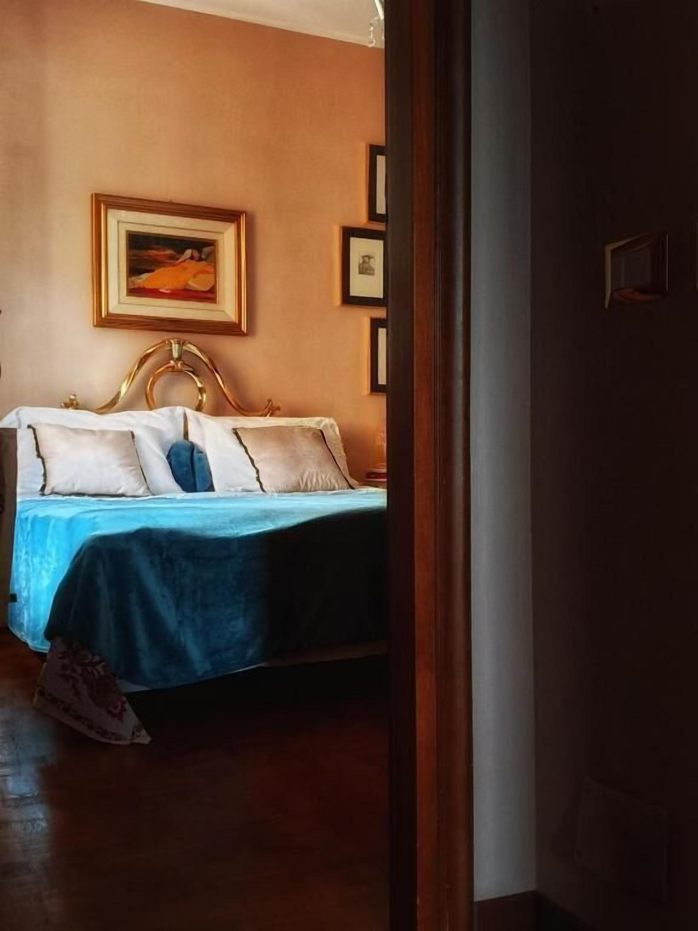 Un dormitorio con una cama, una manta azul y un cuadro en la pared.