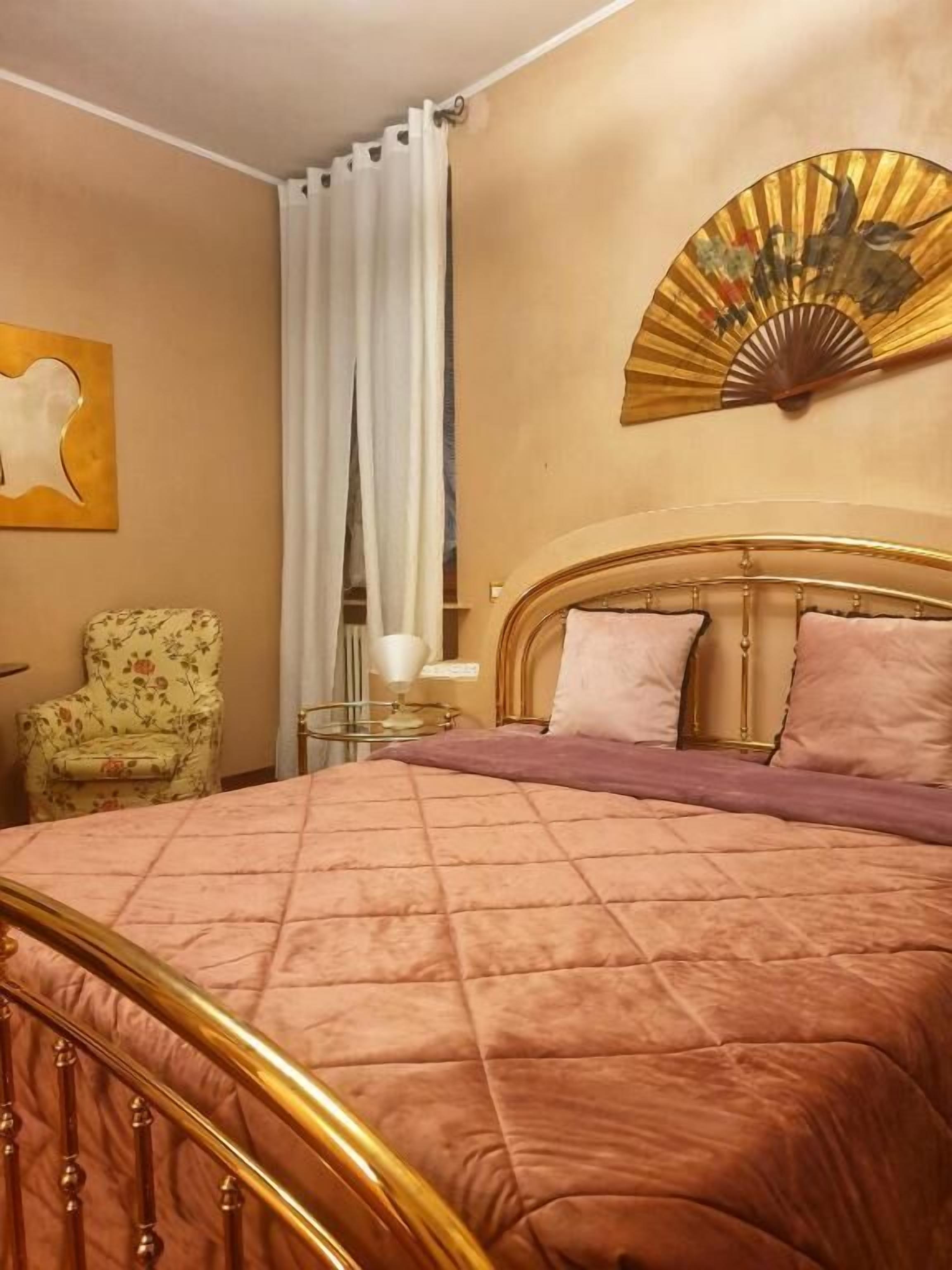A hotel room with a bed, a chair, a bedside table, and a wall decoration.