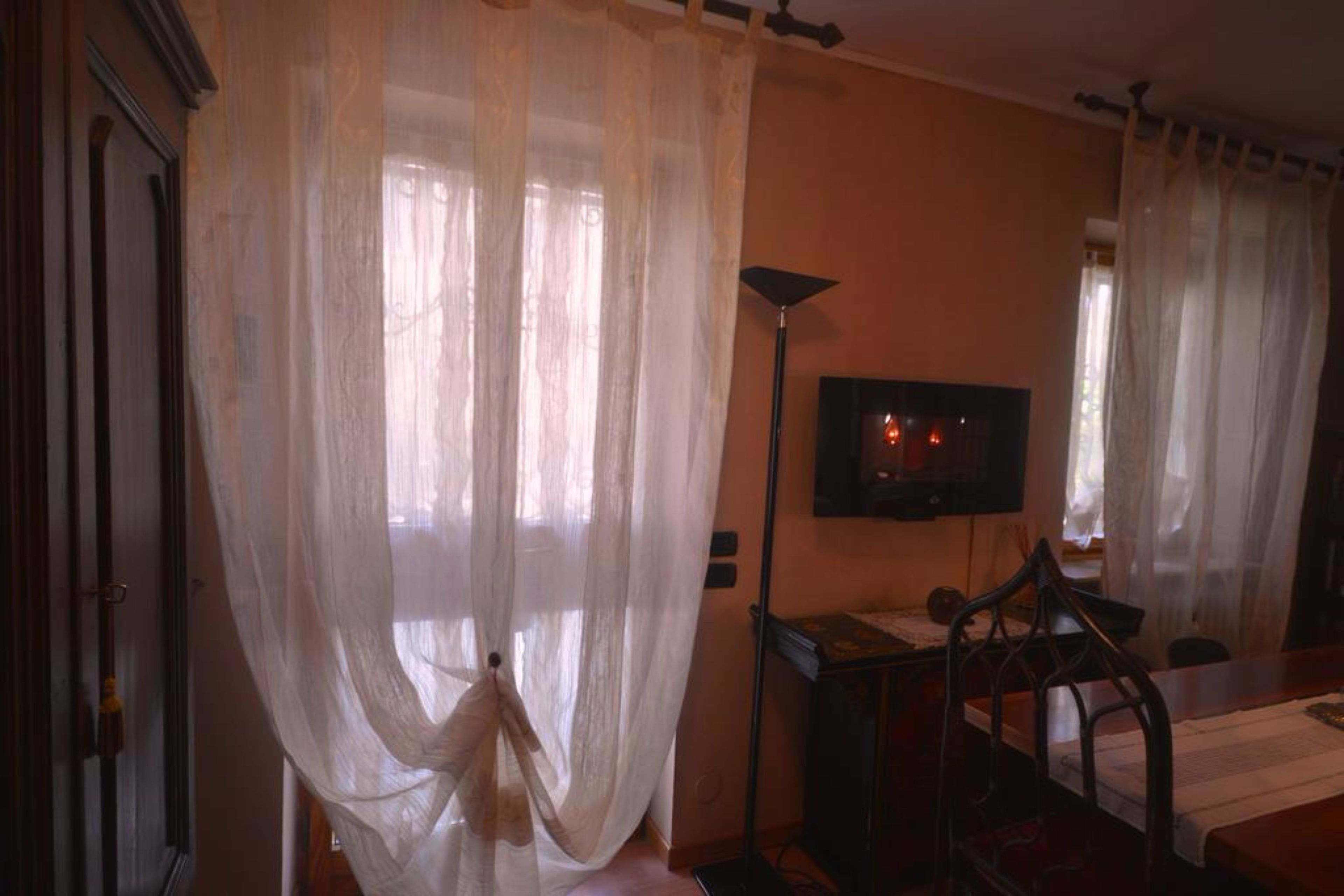 A room with a television on a stand, a chair, and a table.