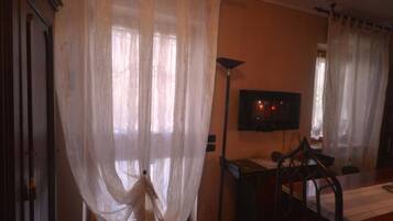 A room with a television on a stand, a chair, and a table.