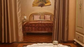 Una camera da letto con un letto, un comodino, una ventaglio decorativo e un comò.