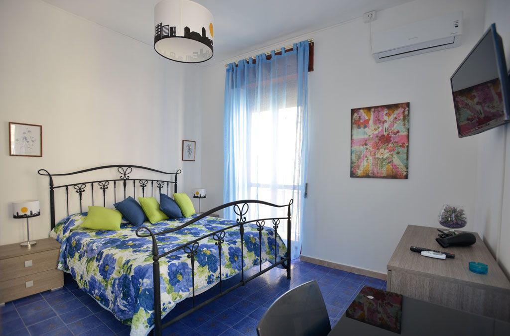 A bedroom with a bed, bedside tables, a desk, and a chair.
