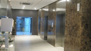 A modern lobby with marble walls, a glass partition, and an elevator. - Premium Residence The Currency Ortigas (Pasig)