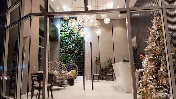 A modern interior with a glass facade, a green wall, and a Christmas tree. - Premium Residence The Currency Ortigas (Pasig)