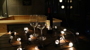A table with two wine glasses and a bottle of wine, surrounded by string lights. - Louis Boutique Hotel (Changwon)