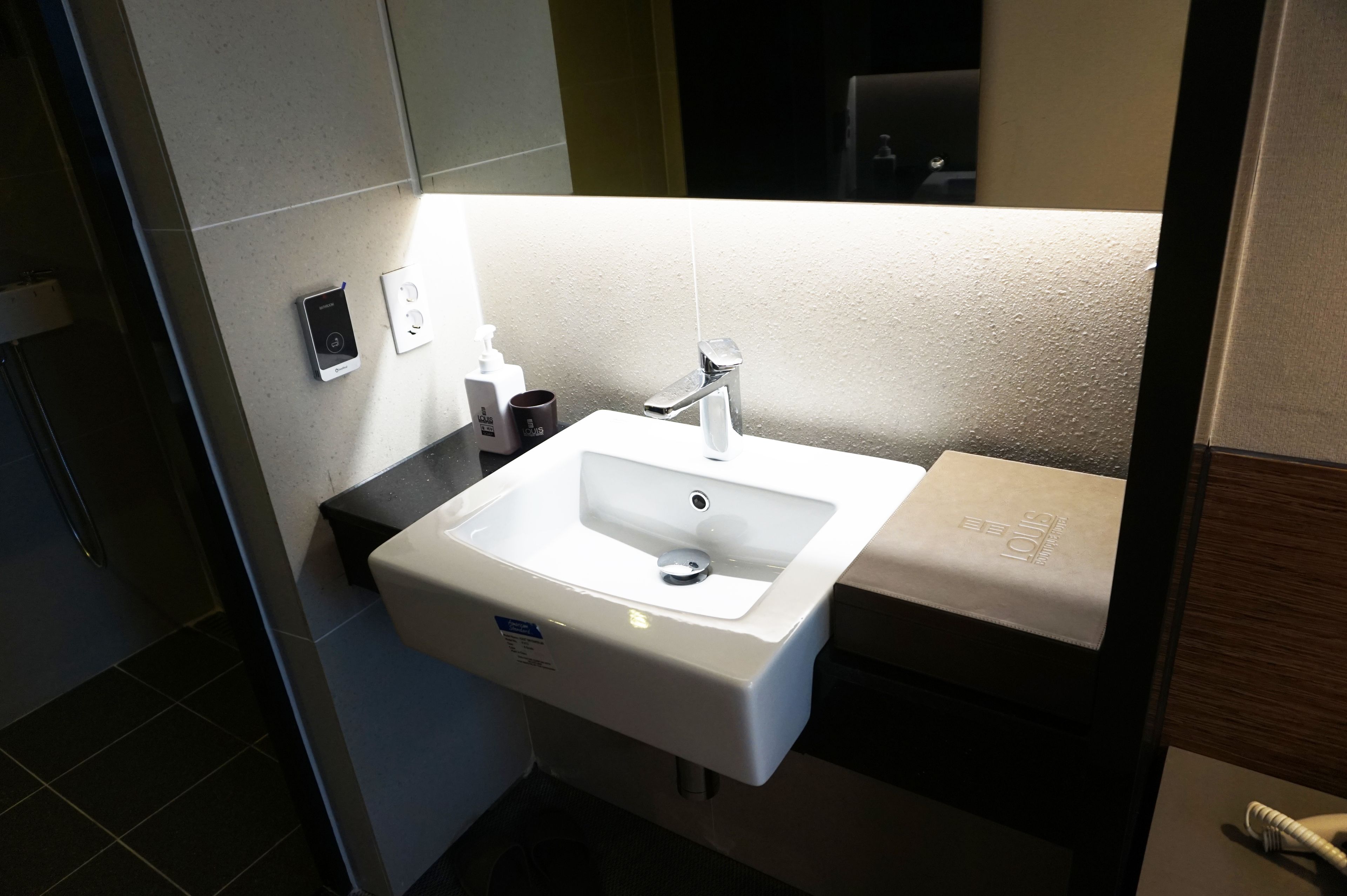 Un bagno con lavandino bianco, uno specchio e un portascopevoli.