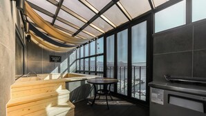 A modern kitchen with a large window, a wooden bench, and a small table. - Louis Boutique Hotel (Changwon)