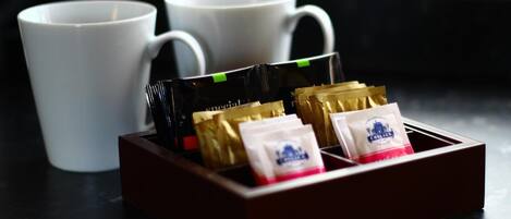 Una bandeja con sobres de café y dos tazas blancas sobre una superficie oscura.