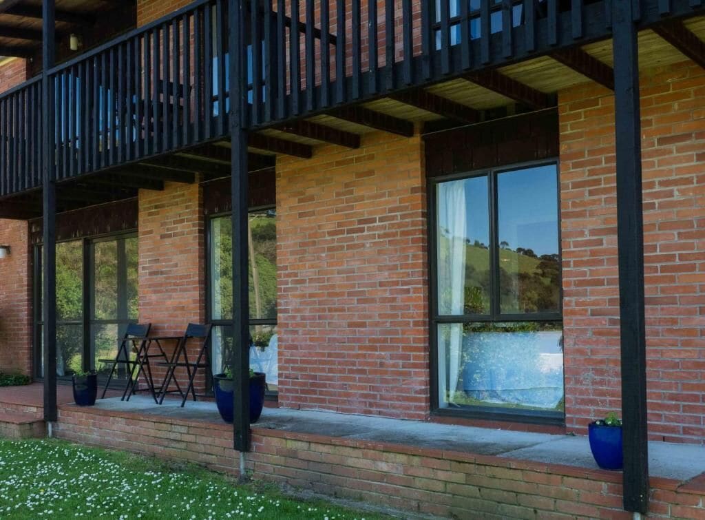 A building with a brick facade, large windows, and a balcony with chairs.
