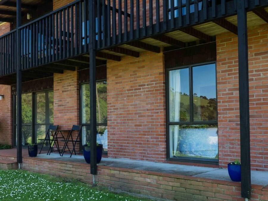 A building with a brick facade, large windows, and a balcony with chairs.
